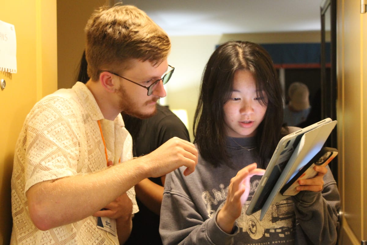 A mentor and a student reviewing work on a tablet together